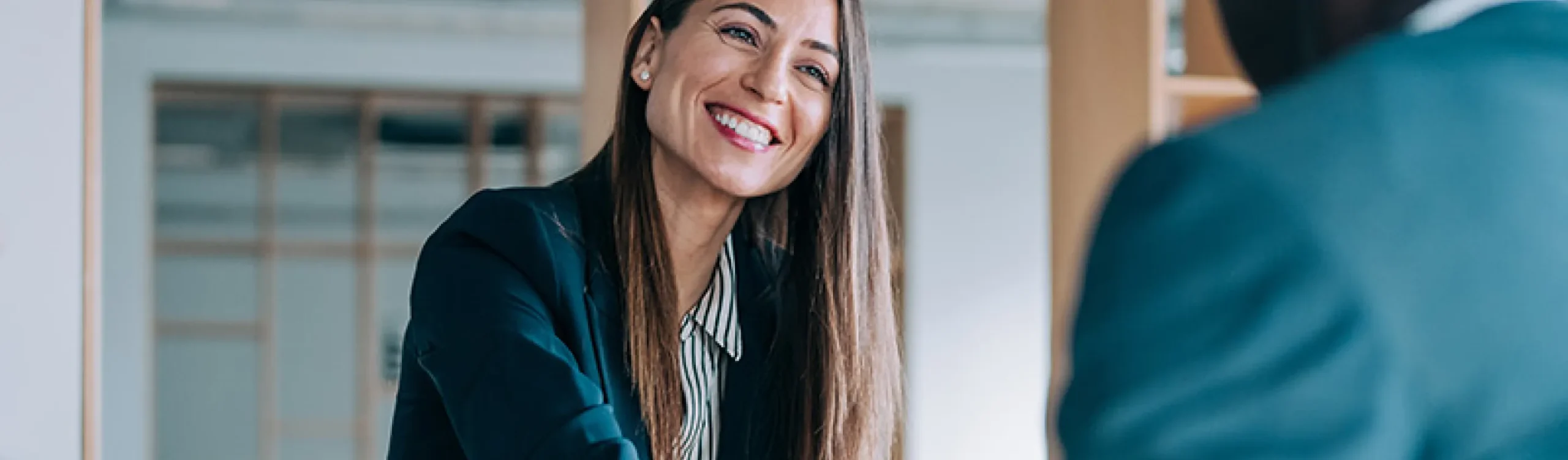 Smiling woman closing deal in an office building.