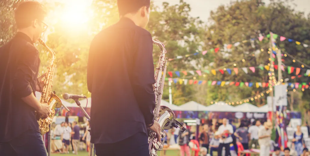 Band playing a concert to a large audience at sunset.