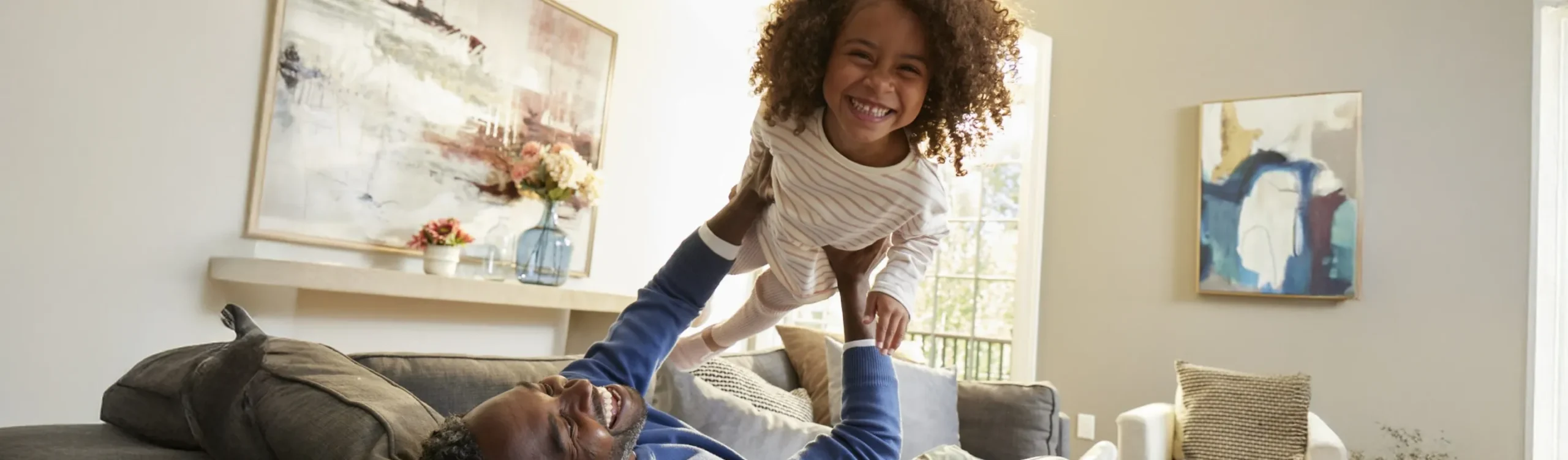 Father and daughter playing on a couch.