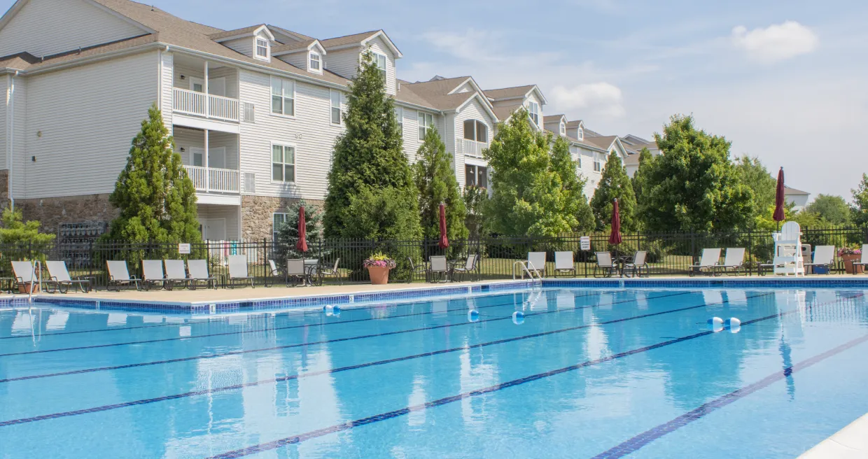 The pool at Meridian Crossing is large and beautiful with lounge chairs and lush landscaping